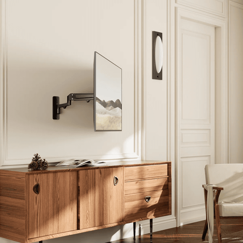 Black articulating wall mount holding a television above a wooden sideboard in a minimalist room.